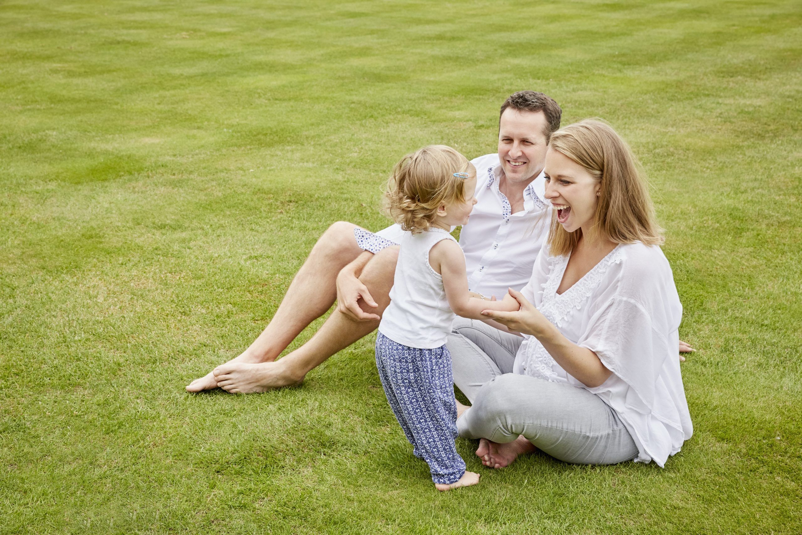 Couple With Daughter On Green Lawn