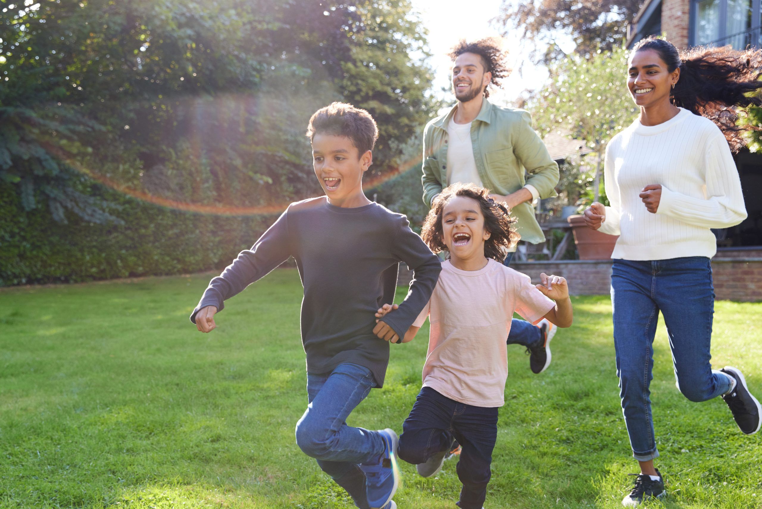 Family Running On Lawn Outside House