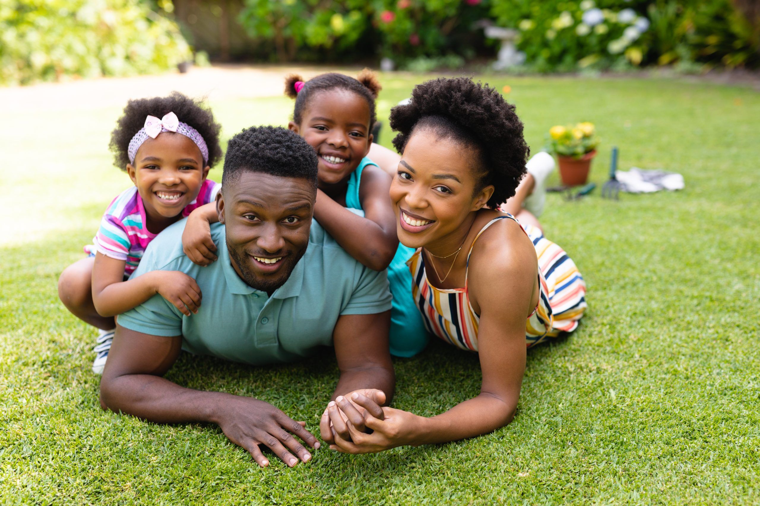 Portrait Of Smiling African American Lying Together On Lawn At Backyard Garden. Family, Love And Togetherness Concept, Unaltered.