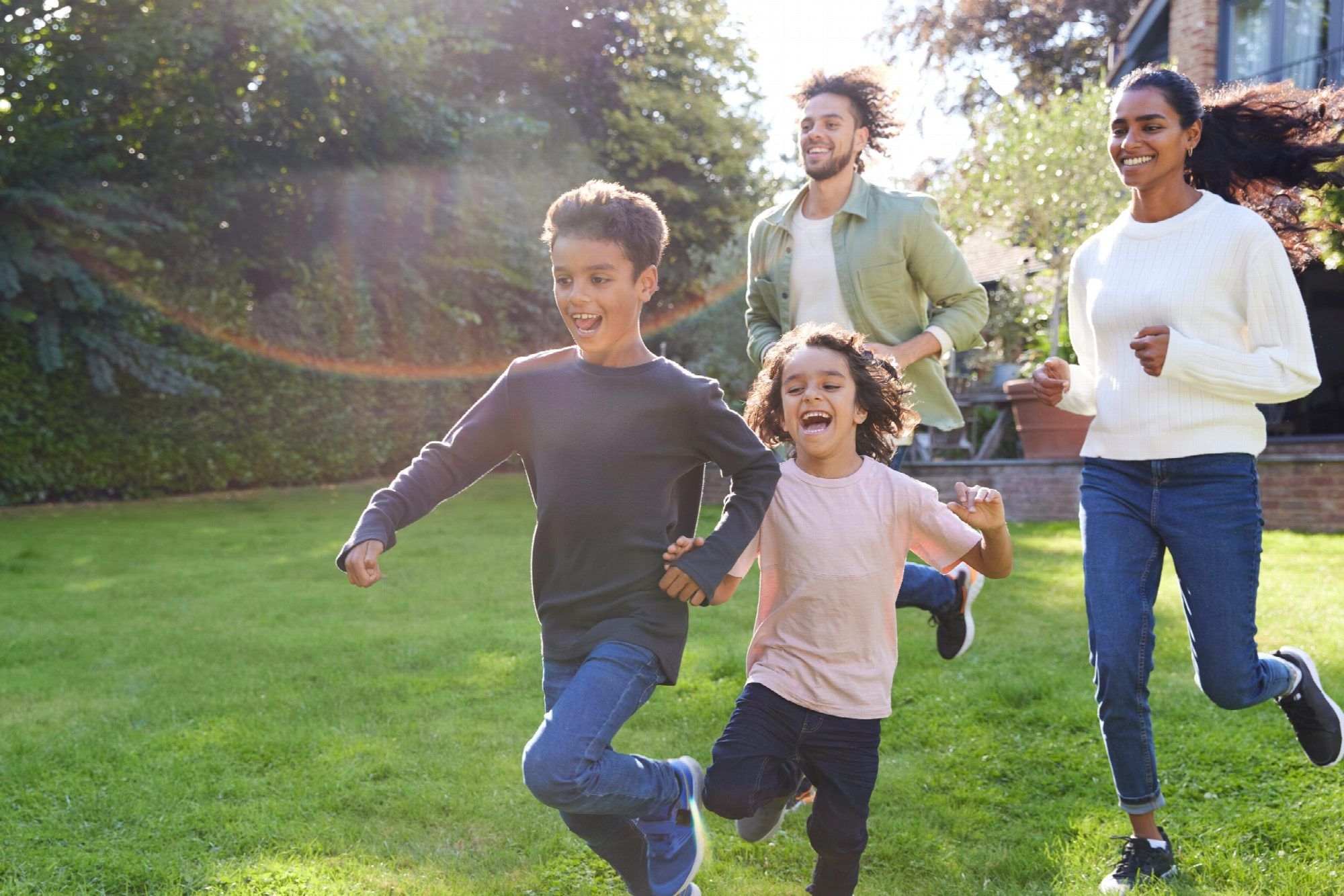 Family Running On Lawn Outside House