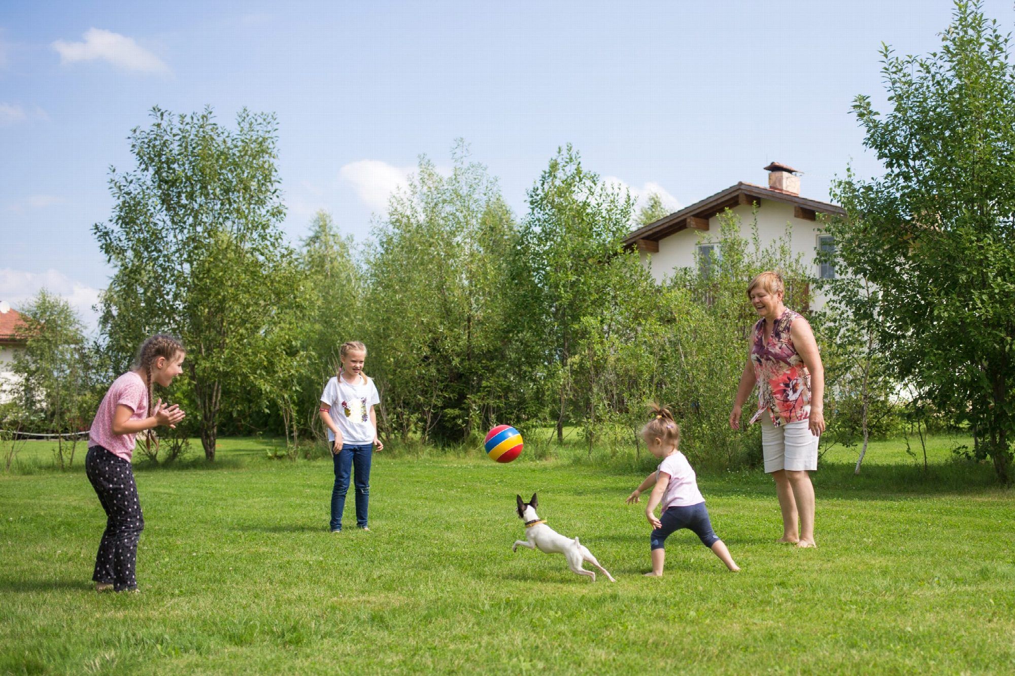 Family Children With Grandmother And Dog Play Ball
