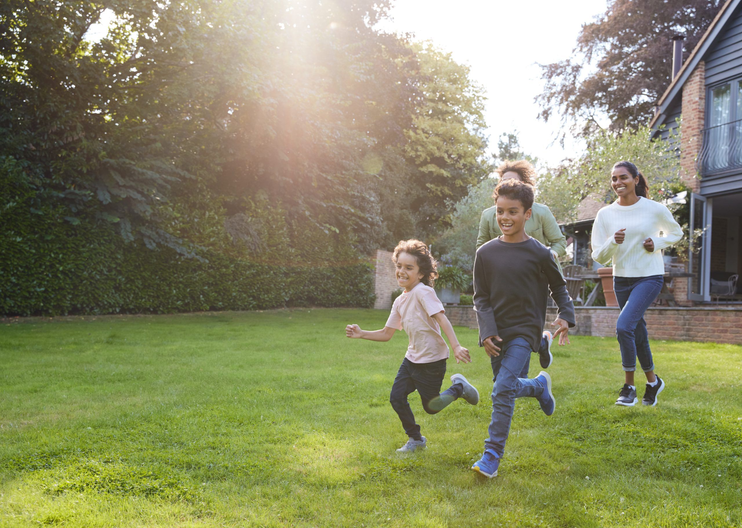 Family Running On Lawn Outside House